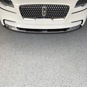 White sedan on a gray full-flake epoxy and polyaspartic-coated garage floor.